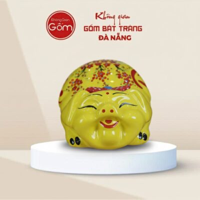 Lợn đất Bát Tràng mắt híp bụng phệ dáng nằm màu vàng gắn nơ do - Ảnh đại diện